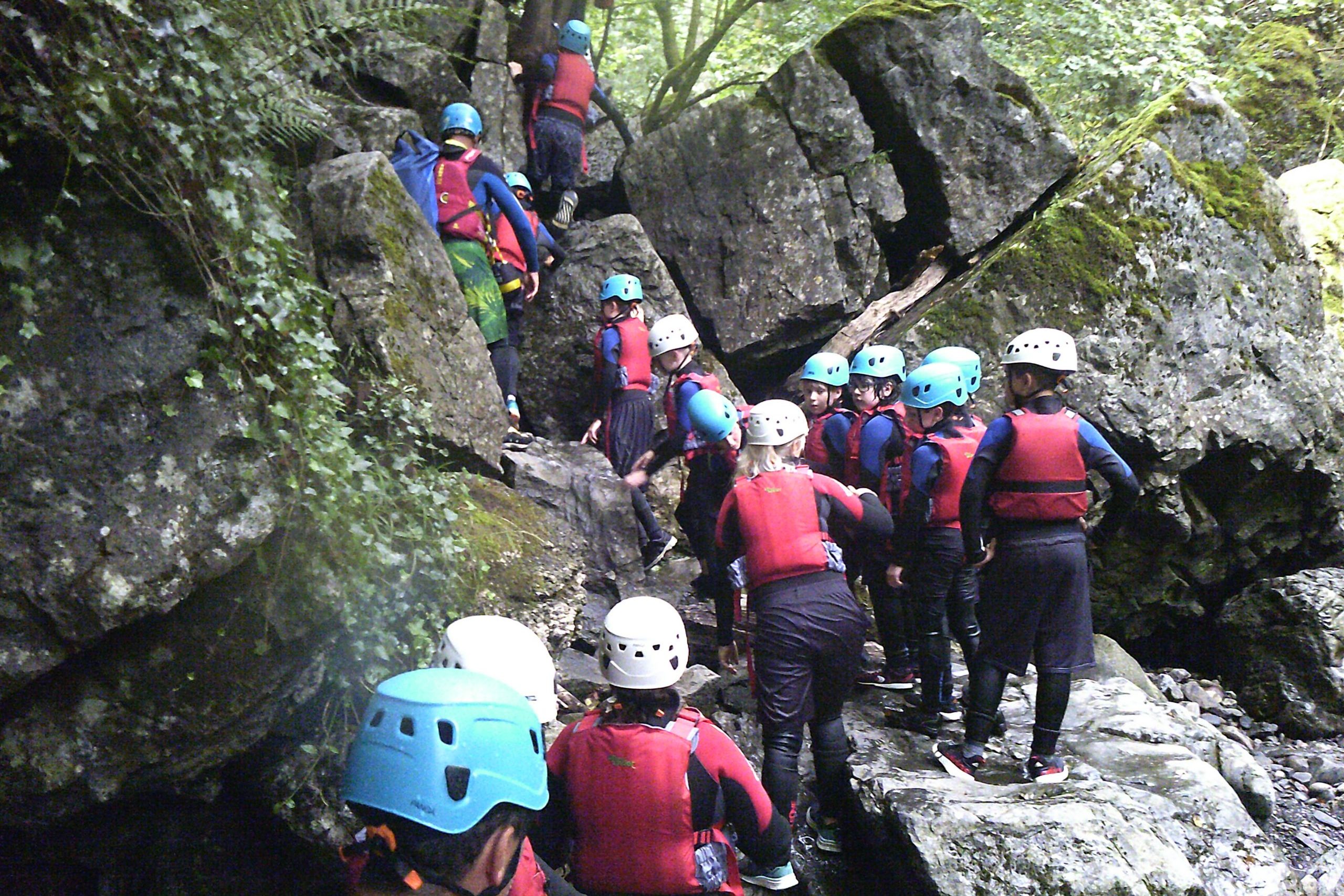 young people scrambling over large rocks in the Sychryd gorge.